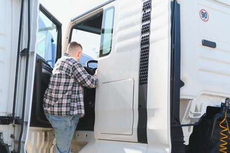Driver climbing into semi truck cabin, preparing for transport. Long haul logistics and professional...