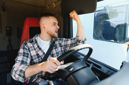 Angry male truck driver shouting and clenching fist, expressing frustration and aggression while...