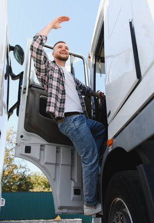 Happy professional truck driver entering the cab of his semi truck, smiling and waving, looking forward to the journeyの写真素材