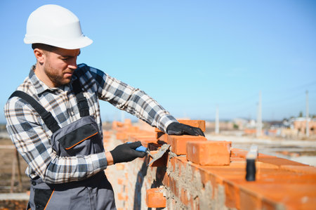 Installing brick wall. Construction worker in uniform and safety equipment have job on building.の写真素材