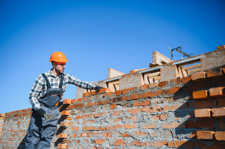 construction mason worker bricklayer installing red brick with trowel putty knife outdoors.