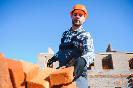Young adult man builder working at object carrying bricks at construction site.