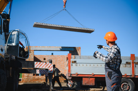 The builder controls the unloading of the panels for the roof of the house with a crane.