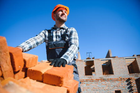 Young adult man builder working at object carrying bricks at construction site.の写真素材