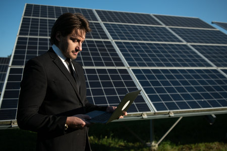 Solar power plant. Man standing near solar panels. Renewable energy.の写真素材