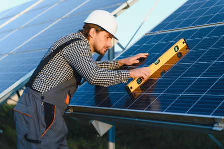 Worker installing solar panel on metal beams at sunny daytime. Renewable and ecological energy. Idea...