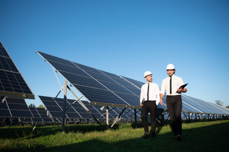 Solar panel farm. Two European engineers inspect solar panels. Workers at a solar panel farm.