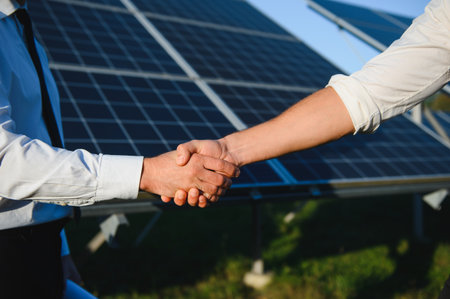Close-up of Two Electrical Engineers shaking hands after working to inspect the installation and maintenance of solar panels in the solar power stationの写真素材
