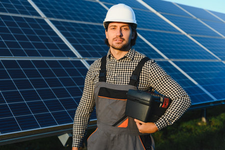 Portrait of a young professional worker in uniform and helmet standing against the background of...