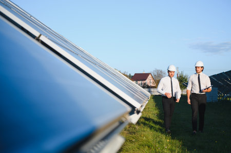 Solar panel farm. Two European engineers inspect solar panels. Workers at a solar panel farm.の写真素材