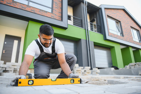 Worker skillfully laying paving stones using a hammer and wearing gloves, showing precision.の写真素材