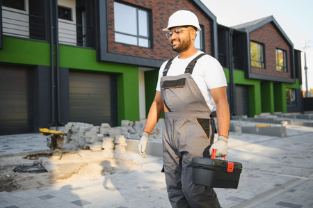 Professional plumber and repairman stands in the background of the cottage. The concept of the job of a repairman or plumber.の写真素材