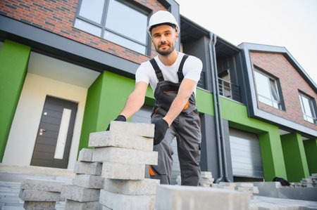 worker lay paving tiles, construction of brick pavement, men's hands in glovesの写真素材