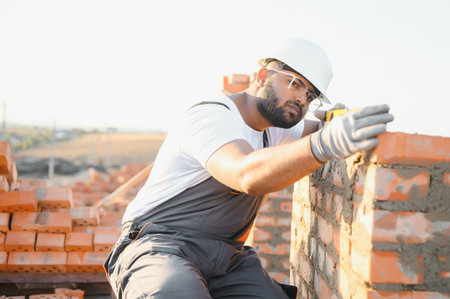 Construction worker man in work clothes and a construction helmet. Portrait of positive male builder in hardhat working at construction site.の写真素材