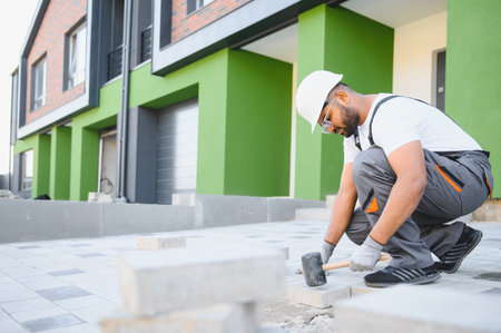 Indian worker lay paving tiles, construction of brick pavement, men's hands in glovesの写真素材