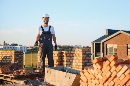 Installing brick wall. Construction worker in uniform and safety equipment have job on building.の写真素材