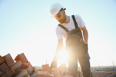Man bricklayer installing bricks on construction site.