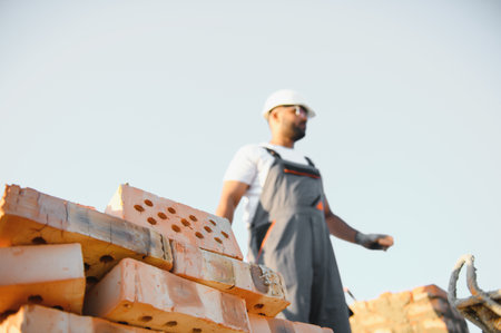 Construction worker man in work clothes and a construction helmet. Portrait of positive male builder in hardhat working at construction site.の写真素材