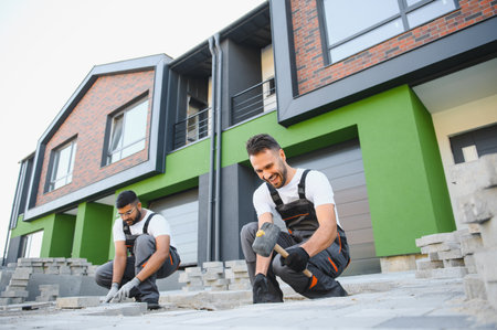 Two workers are laying paving stones near the house.の写真素材
