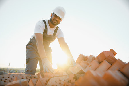 Installing brick wall. Construction worker in uniform and safety equipment have job on building.の写真素材