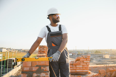 Construction worker man in work clothes and a construction helmet. Portrait of positive male builder...