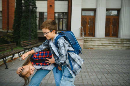 Happy school kids friends boy and girl with backpacks walking and laughing having fun together near school building outside outdoor after lessons.の写真素材