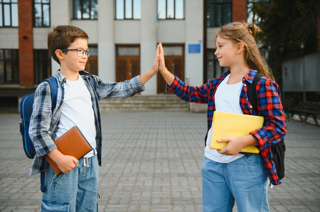 Happy children giving high five to each other standing near school outdoorsの写真素材