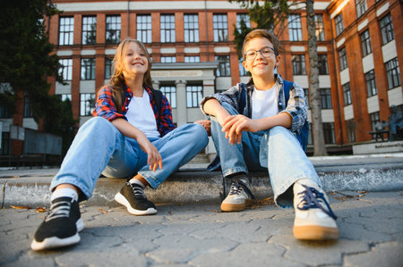 Two, little child with backpack near the school, after finished lesson and speak with each other.の写真素材