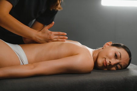 Masseur massaging back and shoulder blades of young woman lying on massage table. Concept of massage spa treatments.の写真素材