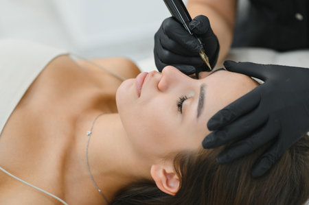 Beauty masters hands do permanent eyebrow makeup. Eyebrow microblading is performed using...