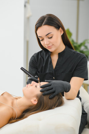Cosmetologist doing permanent makeup eyebrows. Care and beauty concept.の写真素材