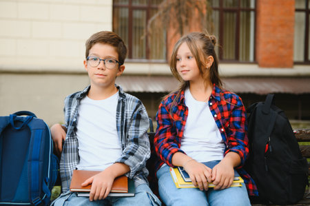 Children read books sitting on bench in school yard. Back to school. Beginning of school lessons.の写真素材
