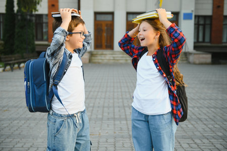 Happy school kids friends boy and girl with backpacks walking and laughing having fun together near school building outside outdoor after lessons.の写真素材