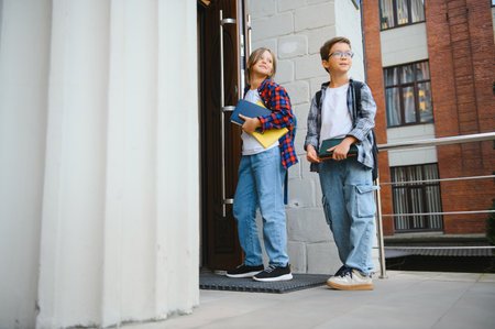 children entering school opening big wooden door. Boys with backpacks by school doorstep on sunny day. Beginning of academic year. Image with selective focusの写真素材