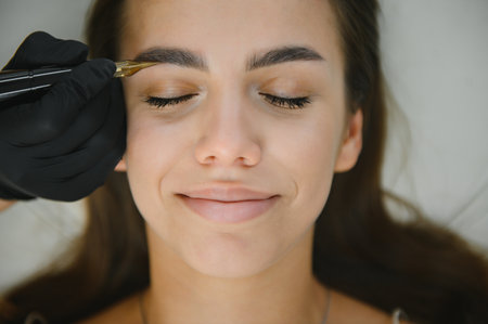 hands of the master who performs the procedure of permanent makeup of eyebrows view from above. Permanent eyebrow makeup PMU for brunettes.の写真素材