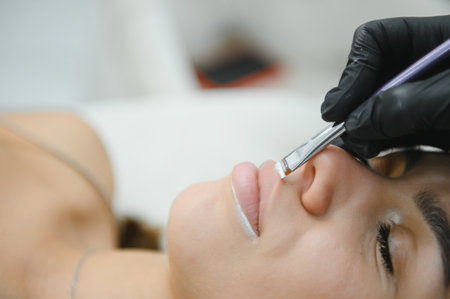 Woman beautician prepares the patient, a young woman, for permanent makeup lips, drawing the boundaries of a pencil in the office.の写真素材