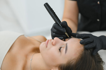 hands of the master who performs the procedure of permanent makeup of eyebrows view from above. Permanent eyebrow makeup PMU for brunettes.の写真素材