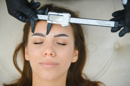 Beauty master measuring eyebrows with calipers before powder permanent makeup. Closeup shot.の写真素材
