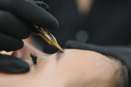Beauty masters hands do permanent eyebrow makeup. Eyebrow microblading is performed using manipulator handle and special nozzle with needles.の写真素材