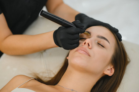hands of the master who performs the procedure of permanent makeup of eyebrows view from above. Permanent eyebrow makeup PMU for brunettes.の写真素材