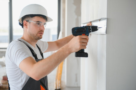 Handsome young male builder in hard hat, while working at construction siteの写真素材