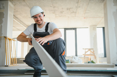 man measuring plasterboard sheet for interior construction.の写真素材