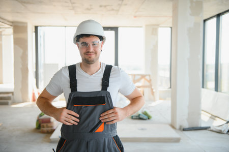 Young man builder wearing hardhat at construction site.