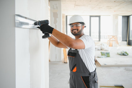 Construction worker installing metal profile for interior partition wall, while building a new house or renovation process, viewed from his backの写真素材