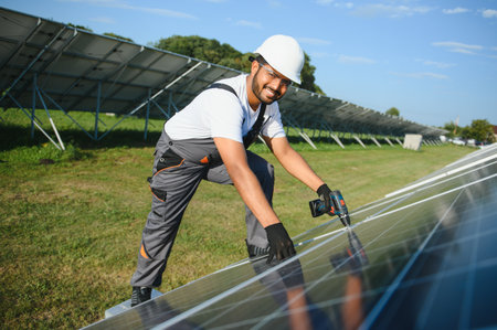 An Indian worker in uniform and with tools works on a solar panel farm.の写真素材