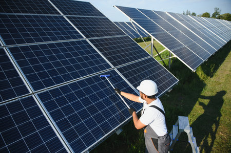 A young Indian cleaning service worker cleans solar panels.