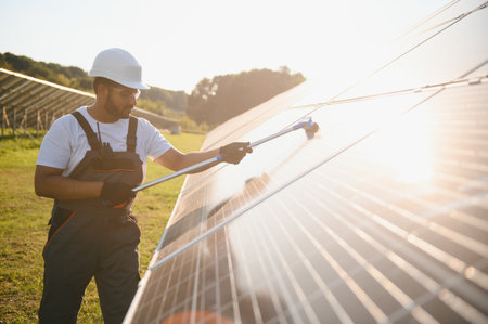 Professional worker cleans solar panels with brush, green electric power technology.