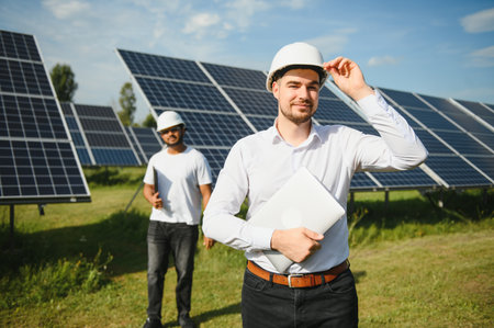 Solar power plant with two engineers walking and examining photovoltaic panels. Concept of alternative energy and its service.の写真素材