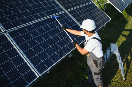Handyman cleaning solar panels form dust and dirt.
