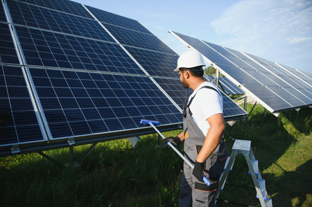 A young Indian cleaning service worker cleans solar panels.